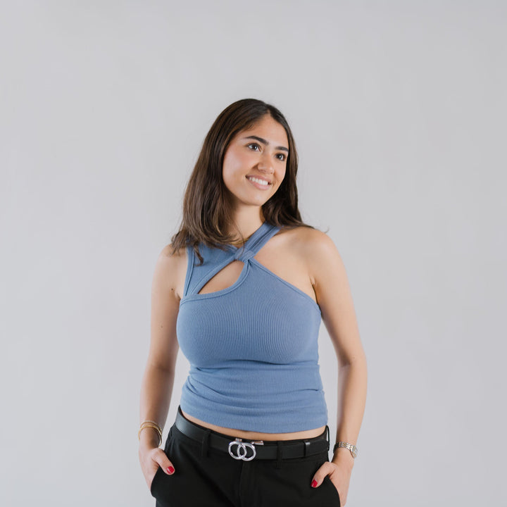 Affra Black leather adjustable women’s belt with silver double-ring buckle styled with black pants and a blue halter top against a plain background