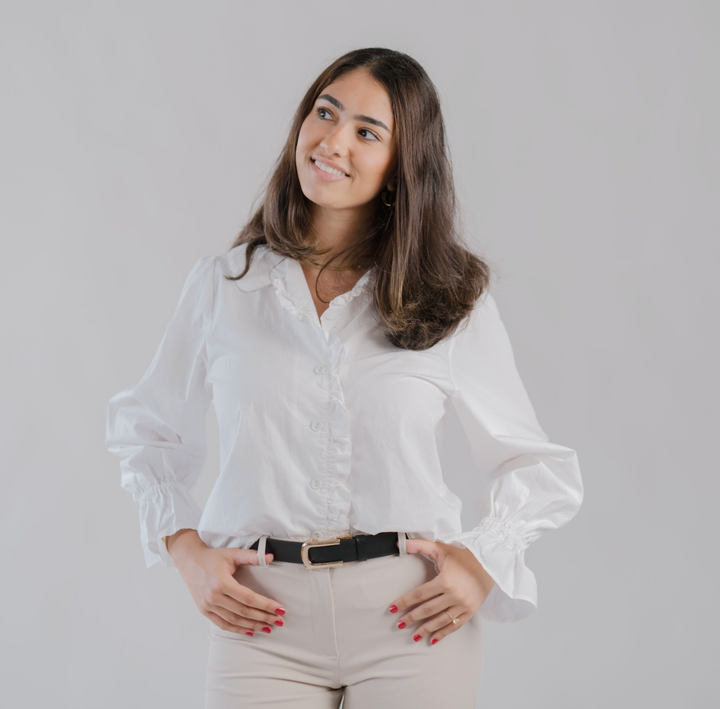 Affrā black leather adjustable belt with gold rectangular buckle worn with white trousers and blouse