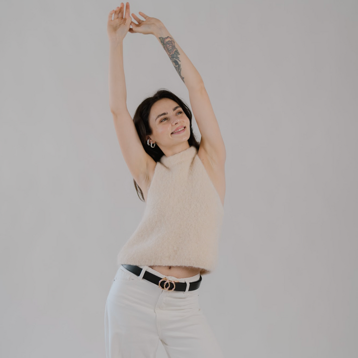 Affra Black leather adjustable women’s belt with gold double-ring buckle styled with white pants and a beige knit sweater