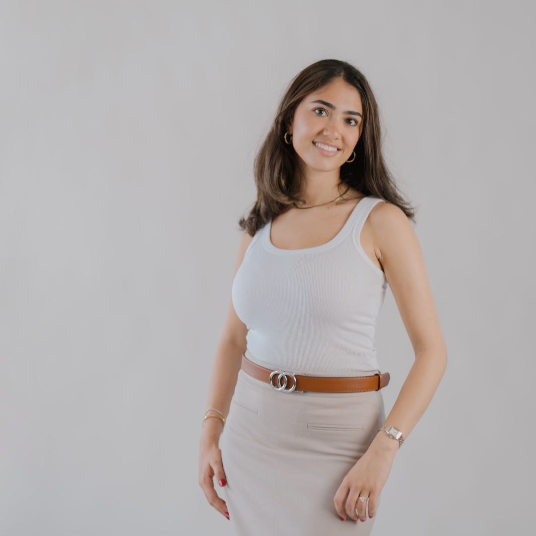 Affra tan leather adjustable women’s belt with silver double-ring buckle styled with a white tank top and beige skirt